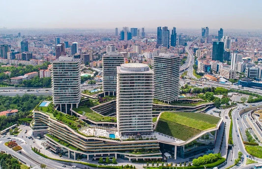 A panoramic distant view of the Raffles Istanbul hotel tower rising elegantly above the city skyline within the modern Zorlu Center complex, set against the backdrop of the Bosphorus Strait in Istanbul.