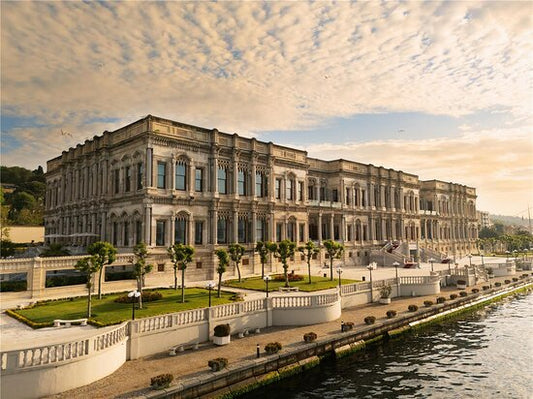 A stunning exterior view of the historic Çırağan Palace Kempinski on the Bosphorus in Istanbul, showcasing its 19th-century marble architecture and luxury infinity pool.